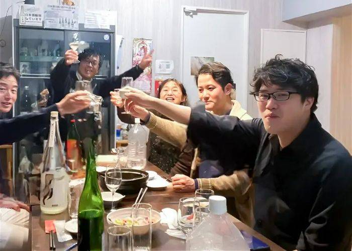 A group of people raising their sake cups to cheers.